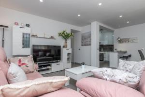 a living room with two pink chairs and a tv at New Modern 3BR with terrace in Fuengirola Centre in Fuengirola