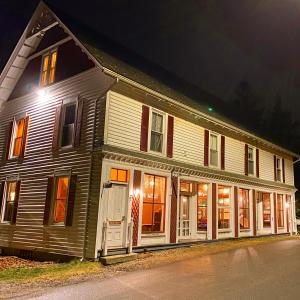 uma casa grande com portas brancas e janelas à noite em Harbor House Hotel by Umaniii in Jonesport Maine em Jonesport