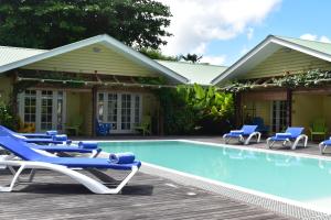 a pool with lounge chairs and a house at Residence Praslinoise in Grand'Anse Praslin