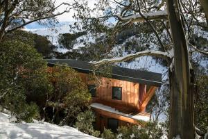 a log cabin in the woods in the snow at 10 Maisonettes in Falls Creek