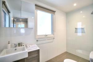 a white bathroom with a sink and a mirror at 10 Maisonettes in Falls Creek