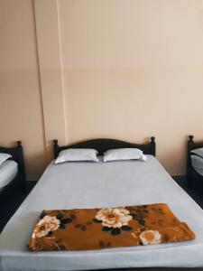 a bed with a brown blanket with flowers on it at Nhà Nghỉ Minh Quân in Ha Tien