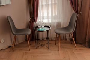 2 Stühle und ein Tisch mit Vase drauf in der Unterkunft Espresso in Myrhorod