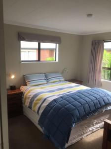 a bedroom with a bed with a blue comforter and a window at Terrific house on totara drive in Twizel