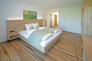 um quarto com uma cama grande e piso em madeira em Gasthof Berger em Sankt Peter