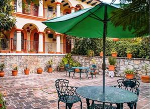 una mesa con una sombrilla verde en el patio en Hotel Rincon Del Arco en San Cristóbal de Las Casas