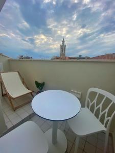 une table et des chaises blanches sur un balcon avec une tour d'horloge dans l'établissement SUITE 168, à Pescara