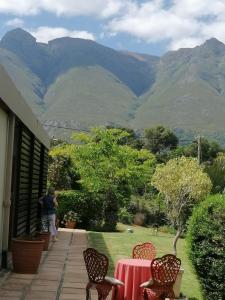 a table and chairs with mountains in the background at Aanhuizen Guest House in Swellendam