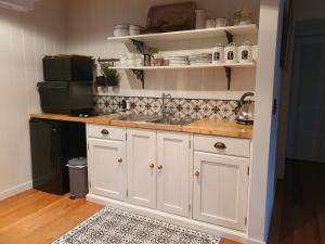 a kitchen with white cabinets and a sink at Gibbston Boathouse with Outdoor Bath in Gibbston