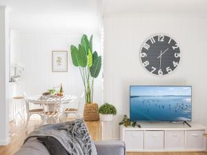 sala de estar con TV, mesa y reloj en Villa Ellisa 4 beautiful unit with beautiful water views at Little Beach, en Nelson Bay