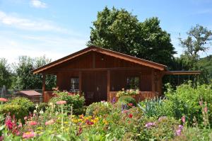 ein kleines Holzhaus in einem Garten mit Blumen in der Unterkunft Ferienhof Spiegel in Hilders