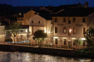 a group of buildings next to a river at night at Corte Regia Relais & Spa in Valeggio sul Mincio