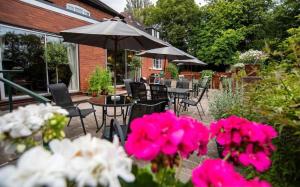 un patio al aire libre con mesas, sillas y flores rosas en Westbourne Lodge, en Birmingham