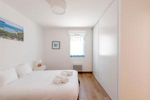 a white bedroom with a bed with towels on it at Résidence Les Suites Du Ferret in Cap-Ferret