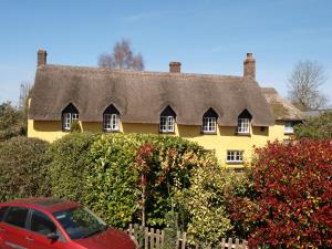 a red car parked in front of a yellow house at Red Lion in Exeter