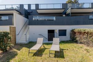 two chairs and a bench in front of a house at Résidence Les Suites Du Ferret in Cap-Ferret