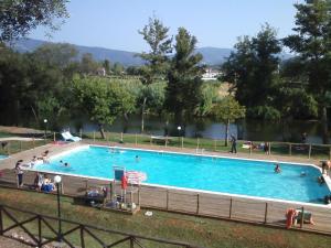 a large swimming pool with people in it next to a river at Casa Rustica in Arganil