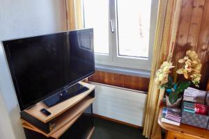 a flat screen tv sitting on a stand in a room at Guntli’s family Guesthouse in Andelfingen
