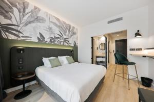 
a bedroom with a bed, chair, and a painting on the wall at Campanile Smart Lyon Est - Eurexpo Bron Aviation in Saint-Priest
