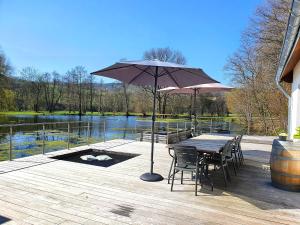 una terraza de madera con mesa, sillas y sombrilla en Les étangs du Thioux GUEST HOUSE en Malmedy