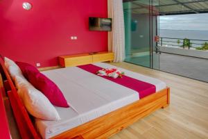 um quarto com uma cama com uma parede vermelha em Hôtel Villa Les Orchidées em Ambatoloaka