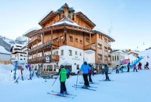 a group of people on skis in front of a ski lodge at Hotel Mesdi in Arabba