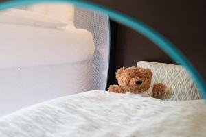 un ours en peluche assis au-dessus d'un lit dans l'établissement Sorell Hotel St. Peter, à Zurich