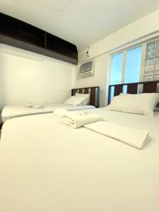 two beds in a room with white sheets at E Relaxed Haven Transient House in Manila