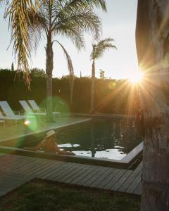 a woman sitting in a pool of water with the sun at Herdade da Rocha - Boutique Lodge in Crato