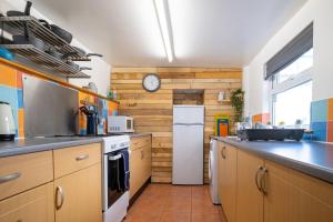 a kitchen with wooden walls and a white refrigerator at Spaven Mor, Near Penzance Stations, 3 bedroom home in Penzance