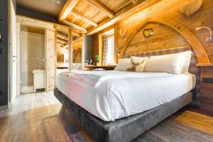 a bedroom with a large bed with a wooden ceiling at John Luxury Suites in Folgaria