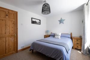 a bedroom with a bed with a blue blanket at Spaven Mor, Near Penzance Stations, 3 bedroom home in Penzance