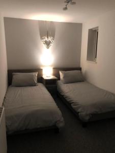 a room with two beds and a light on the wall at Driftwood Apartment - Skegness in Skegness