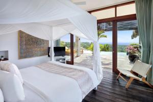 a bedroom with a white bed and a balcony at Hidden Hills Villas - Small Luxury Hotels of The World in Uluwatu +142 photos