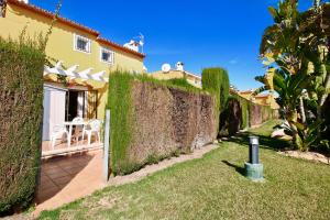 un patio trasero con una valla, una mesa y sillas en Residencial Datiler El Retiro, en Denia