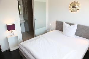 1 dormitorio con cama blanca y espejo en Hotel Haus Berger, en Colonia