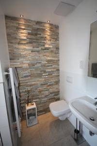 a bathroom with a white toilet and a stone wall at Hotel Haus Berger in Cologne