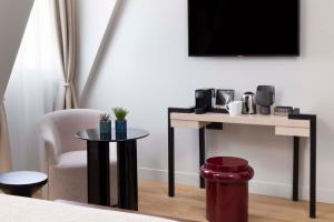 Habitación con mesa, silla y TV. en Hotel Le 37 Bis, en Neuilly-sur-Seine