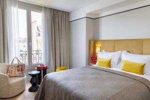 Un dormitorio con una cama y una silla y una ventana. en Hotel Le 37 Bis, en Neuilly-sur-Seine