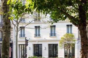 um edifício branco com janelas e árvores em Hotel Le 37 Bis em Neuilly-sur-Seine