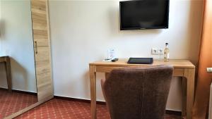 a living room with a tv and a chair at Altstadthotel Goldene Kugel in Waren