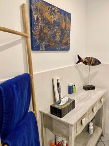 a room with a table and a blue chair and a painting at ART'APPART in Narbonne