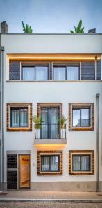 a white building with windows and potted plants at Nell&And&Jess in Espinho