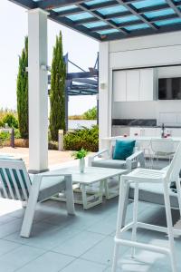 un patio con muebles blancos, mesa y sillas en Seafront Villa Maya by Ruidoso Luxury, en Ayia Napa