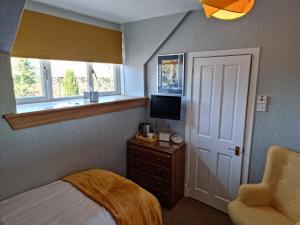 a bedroom with a bed and a television and a chair at Drumdale Bed and Breakfast in Inverness