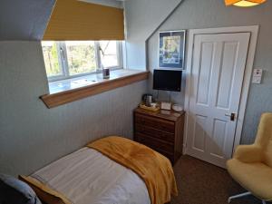 a bedroom with a bed and a television and a window at Drumdale Bed and Breakfast in Inverness