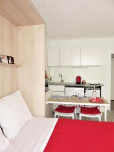 una pequeña cocina con una cama roja y blanca en una habitación en Lumineux Studio 5 mn plages et commerces - Centre-ville - Voiles Blanches avec ascenseur, en La Grande-Motte