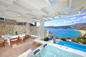 un patio al aire libre con bañera de hidromasaje, mesa y sillas en Luxurious Villa Ostria, en Playa de Elia