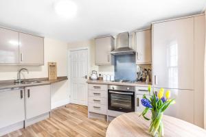 a kitchen with white cabinets and a table with flowers at Bridge House in Totnes