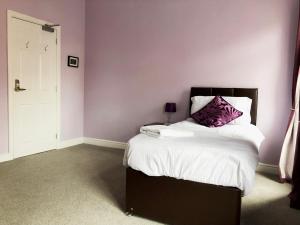 1 dormitorio con 1 cama con pared morada en Sidings Holt - whole house sleeps up to 7 en Crewe